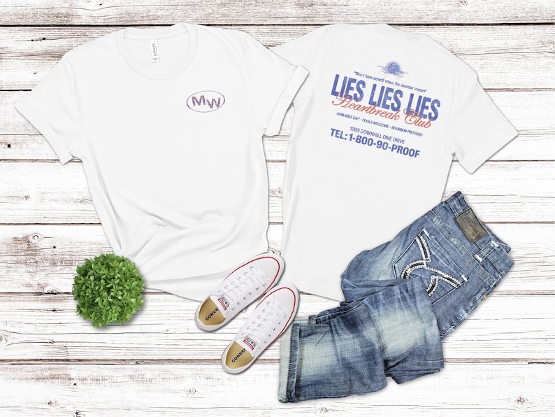 May include: White t-shirts with text and a pair of blue jeans and white sneakers. One shirt has the letters "MW" inside an oval. The other shirt has the text "LIES LIES LIES Heartbreak Club" and a phone number.