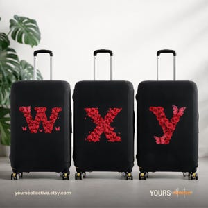 Könnte beinhalten: Drei schwarze Kofferhüllen mit den Buchstaben W, X und Y aus roten Rosen. Der Buchstabe W hat Schmetterlingsakzente. Das Gepäck hat einen Teleskopgriff und Räder. Die Website yours collective.etsy.com ist unten aufgedruckt.