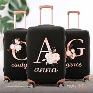 May include: Three black suitcase covers with rose gold details. Each cover displays a large initial, floral design, and a name. The luggage has a rose gold handle and wheels. The text "yours collective" is at the bottom.