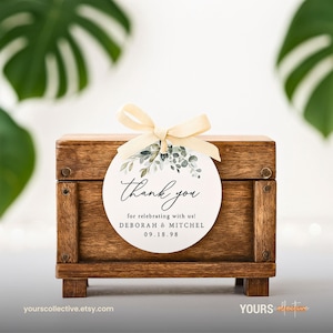 May include: A small, stained wooden box with a decorative tag tied with a cream-colored ribbon. The tag reads "Thank you" with the names Deborah & Mitchel and the date 09.18.98. The tag has a floral design.