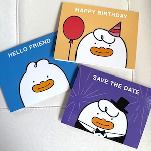 May include: Three greeting cards with cartoon duck illustrations. One card says "HELLO FRIEND" on a blue background. Another says "HAPPY BIRTHDAY" on a yellow background. The third says "SAVE THE DATE" on a purple background.