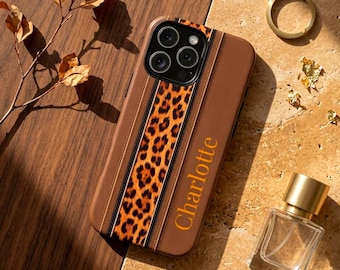 May include: A brown phone case featuring a vertical leopard print stripe and the name Charlotte printed in gold lettering. The case has a cutout for a triple camera system and is designed with a smooth, solid brown finish on the side panels.