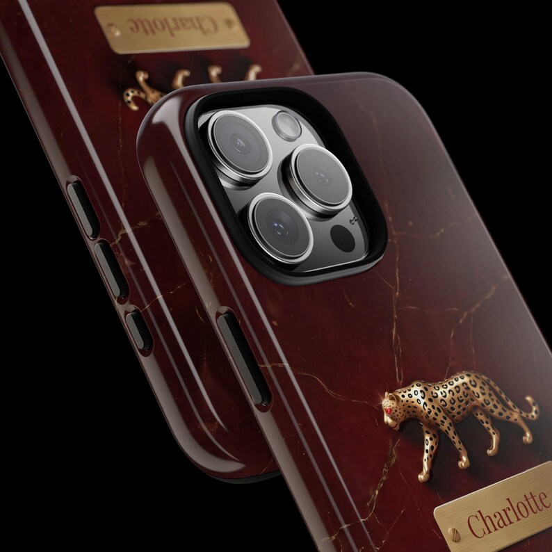 May include: A dark red marble-patterned phone case featuring a gold-toned leopard figurine and a rectangular gold nameplate engraved with the name Charlotte. The case has a black camera cutout and side buttons, with a glossy finish throughout.