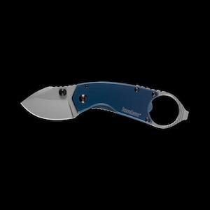 May include: A small, blue and silver folding knife with a curved blade. The knife has a blue handle and a silver blade. The brand name "Kershaw" is printed on the handle. The knife has a finger ring for easy carrying.