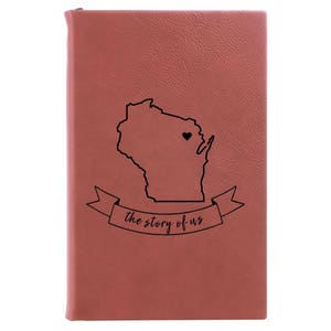 Peut inclure: Un journal en cuir rouge avec un contour noir de l'&eacute;tat du Wisconsin et un c&oelig;ur au centre. Le texte "the story of us" est &eacute;crit sur une banni&egrave;re sous l'&eacute;tat.
