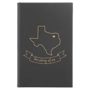 Peut inclure: Un journal en cuir noir avec un contour dor&eacute; de l'&eacute;tat du Texas et un petit c&oelig;ur au centre. Le texte "the story of us" est &eacute;crit en dor&eacute; sous le contour de l'&eacute;tat.