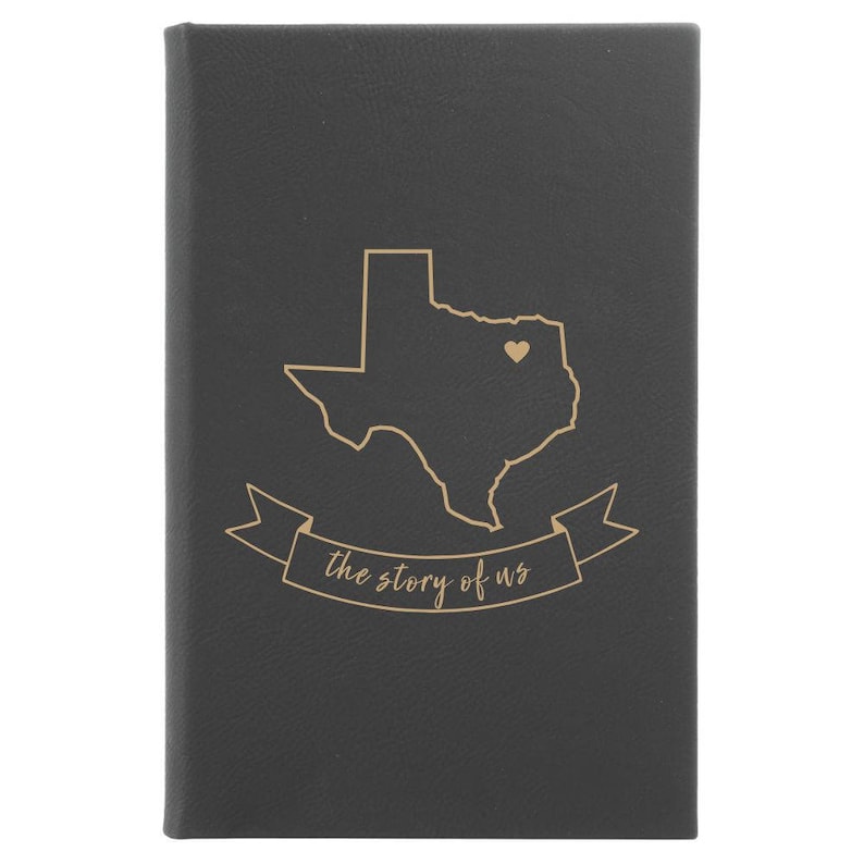 Peut inclure: Un journal en cuir noir avec un contour dor&eacute; de l'&eacute;tat du Texas et un petit c&oelig;ur au centre. Le texte "the story of us" est &eacute;crit en dor&eacute; sous le contour de l'&eacute;tat.
