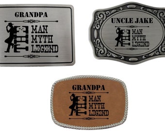 Puede incluir: Tres hebillas de cinturón plateadas con una silueta negra de un hombre de pie con el texto "Man Myth Legend" y un nombre sobre el texto. Las hebillas son rectangulares y tienen un acabado plateado. Las dos hebillas superiores tienen un borde decorativo. La hebilla inferior tiene un fondo de cuero marrón.