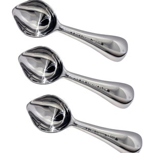 May include: Three silver ice cream scoops with personalized engravings. The scoops are arranged in a vertical stack, with the top scoop reading "Anne's Ice Cream Spoon", the middle scoop reading "Papas Ice Cream Plow", and the bottom scoop reading "Mama's Ice Cream Shovel".