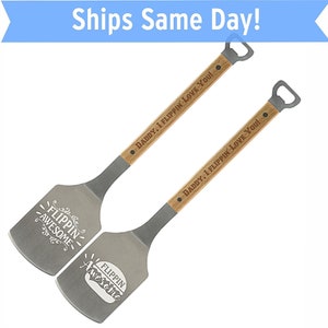 May include: Two wooden handled spatulas with metal blades. The blades are engraved with the text "Flipping Awesome" and the handles are engraved with the text "Daddy, I Flipping Love You!" Each spatula has a bottle opener on the end of the handle.