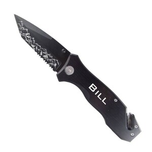 May include: Black pocket knife with a serrated blade and a safety feature. The knife has a mountain design and the name "BILL" engraved on the handle.