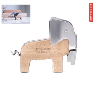 Puede incluir: Un abridor de botellas de madera con forma de elefante con una cabeza de metal plateado y una cola de sacacorchos. El abridor tiene las palabras "ventura orchards" grabadas en el lateral.