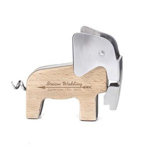 Puede incluir: Un abridor de botellas de madera con forma de elefante con un sacacorchos y un cortador de papel de aluminio de metal plateado. El elefante tiene el texto "Brown Wedding September 14th, 2019" grabado en su lado.