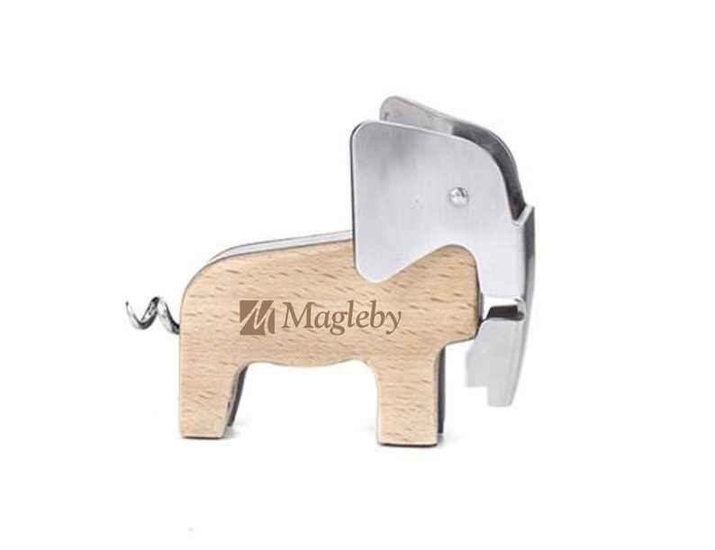 Puede incluir: Un abridor de botellas de madera con forma de elefante con un sacacorchos de metal plateado y un cortador de papel de aluminio. El abridor tiene el texto "Magleby" impreso en el lateral.