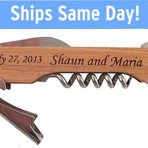 K&ouml;nnte beinhalten: Ein Flaschen&ouml;ffner mit Korkenzieher, Flaschen&ouml;ffner und Kronkorken&ouml;ffner. Der Griff ist aus Holz und mit dem Text "July 27, 2013 Shaun and Maria" graviert.