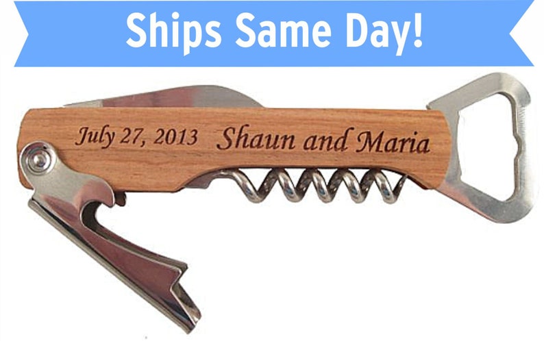 K&ouml;nnte beinhalten: Ein Flaschen&ouml;ffner mit Korkenzieher, Flaschen&ouml;ffner und Kronkorken&ouml;ffner. Der Griff ist aus Holz und mit dem Text "July 27, 2013 Shaun and Maria" graviert.