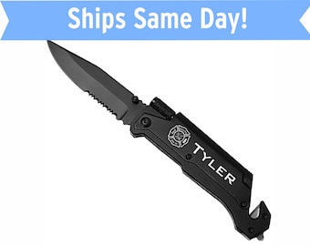 Puede incluir: Cuchillo plegable negro con una hoja dentada, un rompe cristales y un corta cinturones de seguridad. El cuchillo tiene un mango negro con un emblema de bombero plateado y el nombre "TYLER" grabado en él.