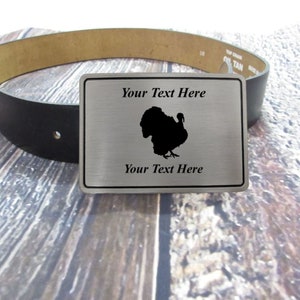 May include: A silver belt buckle with a black silhouette of a turkey and the text "Your Text Here" on a black leather belt.