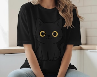 May include: Black t-shirt featuring a cartoon black cat with large yellow eyes. The cat is sitting, and the design is centered on the shirt. The shirt has short sleeves and a crew neck.