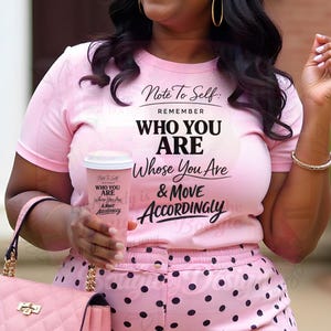 May include: A pink t-shirt with the text "Note To Self: Remember WHO YOU ARE Whose You Are & MOVE ACCORDINGLY." The person is wearing pink polka dot pants and holding a pink coffee cup with the same text.