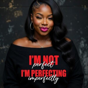 Pu&ograve; includere: Una donna indossa un maglione nero con spalle scoperte con la scritta "I'M NOT perfect I'M PERFECTING imperfectly" in rosso e bianco. Ha i capelli scuri, orecchini a cerchio e rossetto rosa.