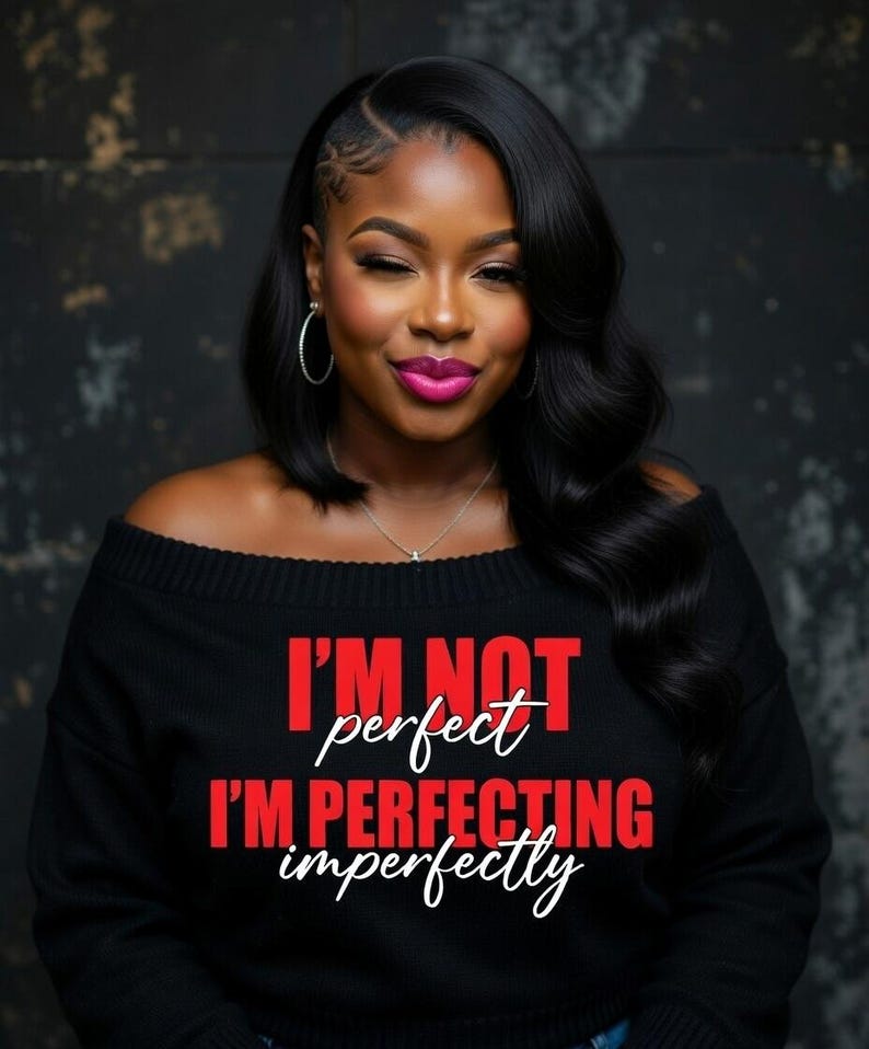 Pu&ograve; includere: Una donna indossa un maglione nero con spalle scoperte con la scritta "I'M NOT perfect I'M PERFECTING imperfectly" in rosso e bianco. Ha i capelli scuri, orecchini a cerchio e rossetto rosa.