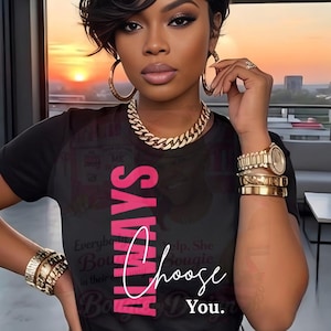 Op de afbeelding: Zwart T-shirt met het woord "ALWAYS" in roze verticaal en "Choose You" in wit. De persoon draagt gouden sieraden, waaronder een ketting, oorringen, armbanden en een horloge.