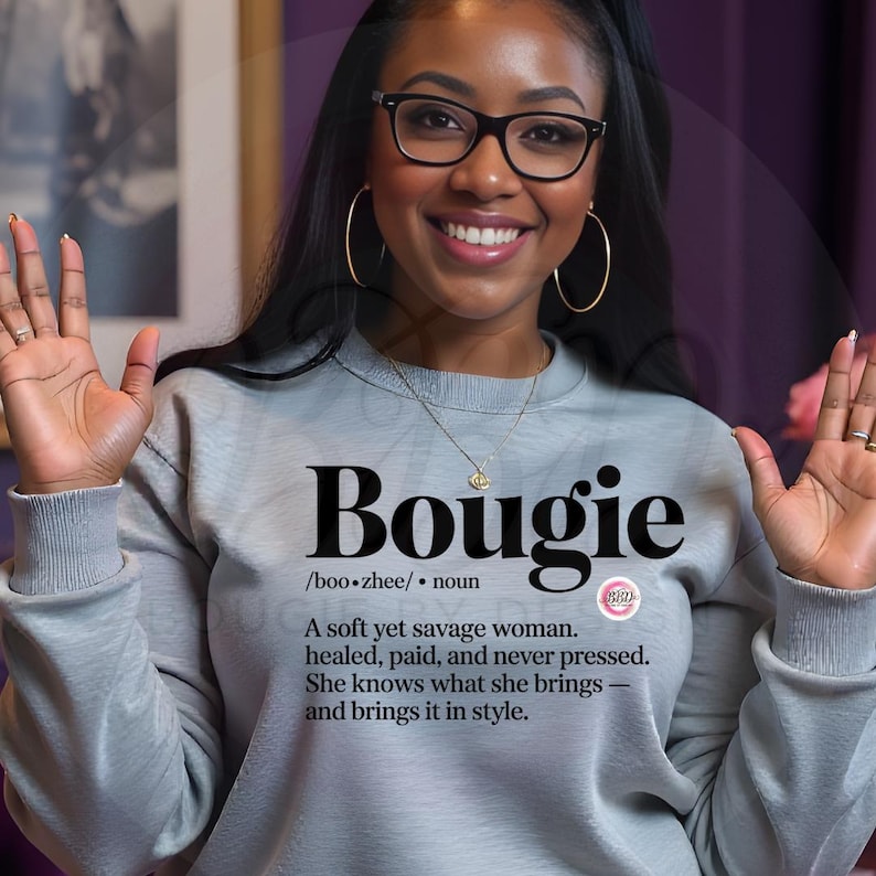 以下が含まれることがあります： 大きな黒い文字で「Bougie」と書かれた、明るい灰色のスウェットシャツ。 「Bougie」の定義が下に印刷されています。 このスウェットシャツは、衣料品ラインの一部です。