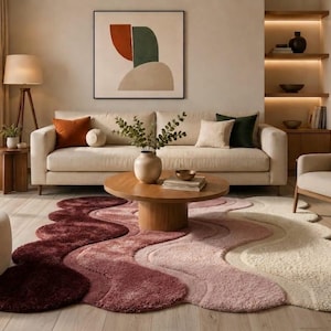 May include: A modern living room with a cream sofa, cushions, and a wooden coffee table. The focal point is a distinctive, wavy rug in burgundy, pink, and cream. The room also includes a floor lamp and artwork, creating a stylish, inviting space.