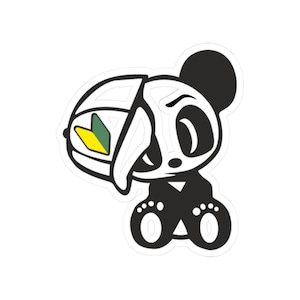 May include: A die-cut sticker featuring a stylized panda bear design. The panda is primarily black and white, with a portion of its head appearing as a skeletal outline. It wears a helmet with a green and yellow beginner driver symbol. The panda is sitting.