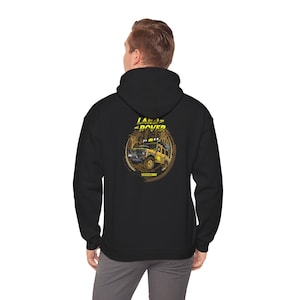 May include: Black hooded sweatshirt featuring a yellow and brown graphic of a Land Rover vehicle. The graphic includes the words "LAND ROVER" in yellow, and the phrase "OFFROAD IN" in yellow.