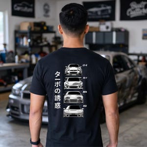 May include: Black t-shirt featuring illustrations of four sports cars: GT-R, RX-7, MK4, and NSX. The shirt also has Japanese text on the left side. The cars are depicted in white, with the text in white.