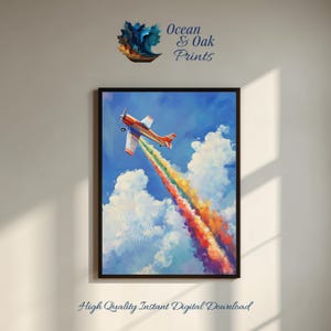 May include: A framed art print depicts an orange and white airplane soaring through a blue sky, leaving a vibrant rainbow contrail. White fluffy clouds surround the plane. The text "Ocean & Oak Prints" is visible. The bottom of the print reads "High Quality Instant Digital Download".
