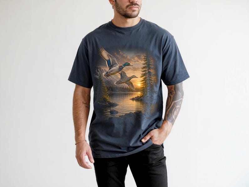 Vintage-inspired wildlife t-shirt featuring realistic flying mallard ducks over a mountain lake at sunrise with retro nature artwork, natural islands, and rustic outdoor aesthetic. Comfort Colors 1717 garment-dyed t-shirt