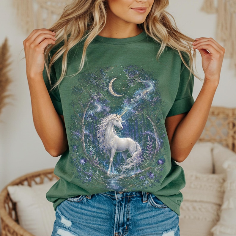 Women’s fantasy graphic t-shirt featuring a  white unicorn standing in an enchanted celestial forest surrounded by glowing moonlight, magical stars, mystical trees, cosmic details, and dreamy fantasy artwork. The design has a vintage-inspired magical aesthetic with fairytale atmosphere, celestial night elements, flowing fantasy illustration, and enchanted woodland scenery printed on a relaxed fit graphic tee for unicorn lovers, fairycore fashion fans, and mystical fantasy style outfits.