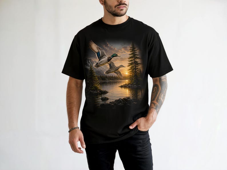 Vintage-inspired wildlife t-shirt featuring realistic flying mallard ducks over a mountain lake at sunrise with retro nature artwork, natural islands, and rustic outdoor aesthetic. Comfort Colors 1717 garment-dyed t-shirt