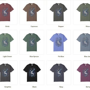 May include: A collection of twelve short-sleeve t-shirts in various colors including brick, espresso, pepper, moss, light green, blue spruce, flo blue, blue jean, graphite, black, navy, and berry, each featuring a graphic of a unicorn and moon.