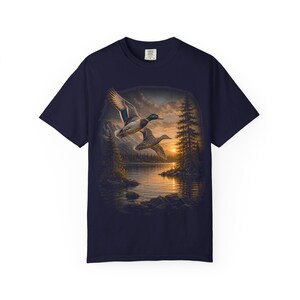 Vintage-inspired wildlife t-shirt featuring realistic flying mallard ducks over a mountain lake at sunrise with retro nature artwork, natural islands, and rustic outdoor aesthetic. Comfort Colors 1717 garment-dyed t-shirt