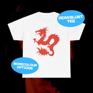 Puede incluir: Camiseta blanca con un diseño de dragón rojo. La camiseta tiene mangas cortas y cuello redondo. El texto en la imagen dice "DEANBLUNT TEE" y "MORECOLOUR OPTIONS".