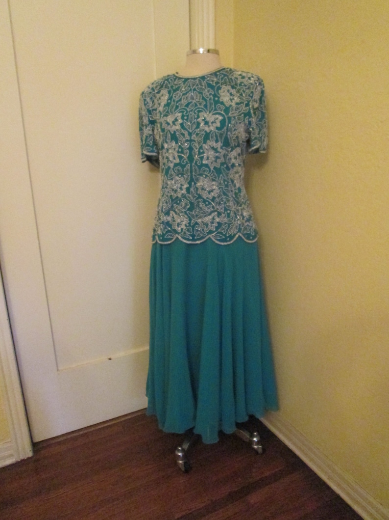 May include: A teal blue formal dress with a white beaded top and a flowing skirt.