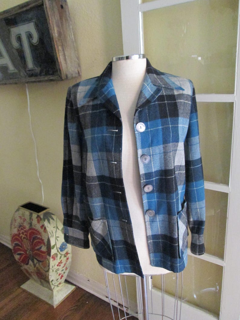 Puede incluir: Chaqueta a cuadros azul, negra y gris con tres botones y dos bolsillos. La chaqueta se exhibe en un maniqu&iacute;. La chaqueta tiene un dise&ntilde;o cl&aacute;sico y a medida.