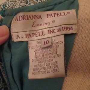 May include: A teal blue dress with a beaded bodice and a white tag that reads "ADRIANNA PAPELL Evening" and "A. PAPELL INC &copy; 1994". The tag also includes size and care instructions.