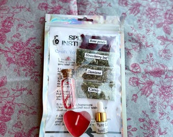 May include: A clear plastic package containing spell crafting ingredients. The package includes small bags of rose petals, strawberry leaf, damiana, and catnip. Also included are a small glass bottle, a red heart-shaped candle, and a small bottle of oil. The text "Spider Lily Witch" is visible.