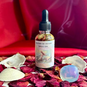 May include: A glass bottle of "Depths of Desire Spell Oil" with a black dropper top. The bottle sits on a bed of dried rose petals, with seashells and a crystal. The background is a deep red fabric.