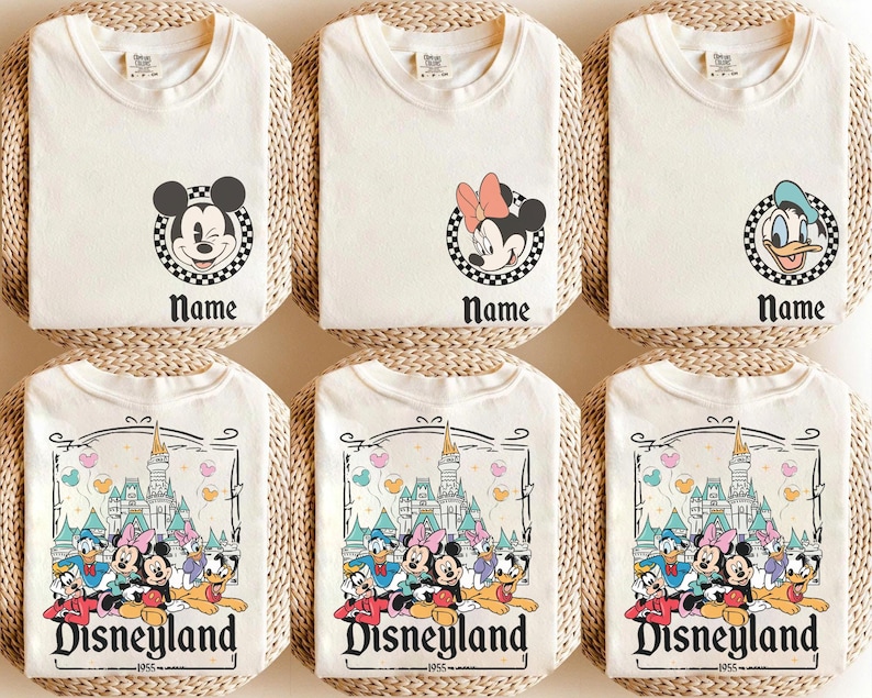 May include: Cream-coloured t-shirts featuring Disney character graphics. Designs include Mickey Mouse, Minnie Mouse, and Donald Duck, each within a chequered circle, and a Disneyland graphic. The word "Name" appears below the character graphics, and "Disneyland 1955" is printed on the bottom.