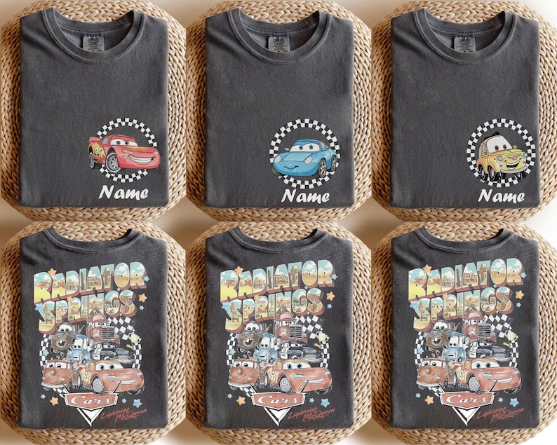 May include: Six dark gray t-shirts with different Cars movie graphics. Three shirts feature a car character with the word "Name" below. The other three shirts have a "Radiator Springs" design with various Cars characters.
