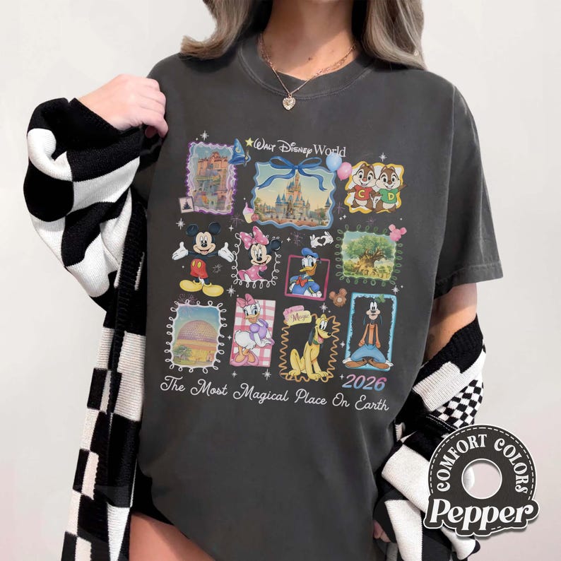 Puede incluir: Camiseta gris oscuro con un gr&aacute;fico colorido de personajes y lugares emblem&aacute;ticos de Walt Disney World. El dise&ntilde;o incluye a Mickey Mouse, Minnie Mouse, el Pato Donald y Chip y Chop, con el texto "The Most Magical Place On Earth" y "2026".