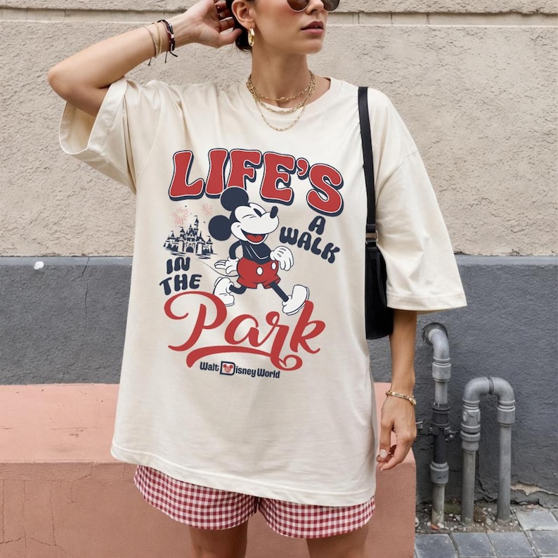 Pu&ograve; includere: T-shirt oversize color crema con grafica di Topolino e la scritta "LIFE'S A WALK IN THE PARK" in rosso e bianco. La maglietta &egrave; abbinata a pantaloncini a quadri rossi e bianchi. Walt Disney World &egrave; stampato in basso.
