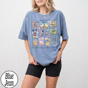 Puede incluir: Una camiseta azul con un dise&ntilde;o de Disney, que muestra varios personajes e iconos del parque. El dise&ntilde;o incluye a Mickey y Minnie Mouse, el Pato Donald y el castillo de Cenicienta. El texto en la camiseta dice "Walt Disney World" y "The Most Magical Place On Earth 2023."