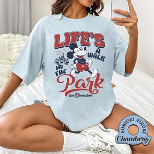 Pu&ograve; includere: T-shirt azzurra con Topolino e la scritta "LIFE'S A WALK IN THE PARK" in rosso e bianco. La maglietta include anche il logo Walt Disney World. Realizzata in tessuto Comfort Colors Chambray.